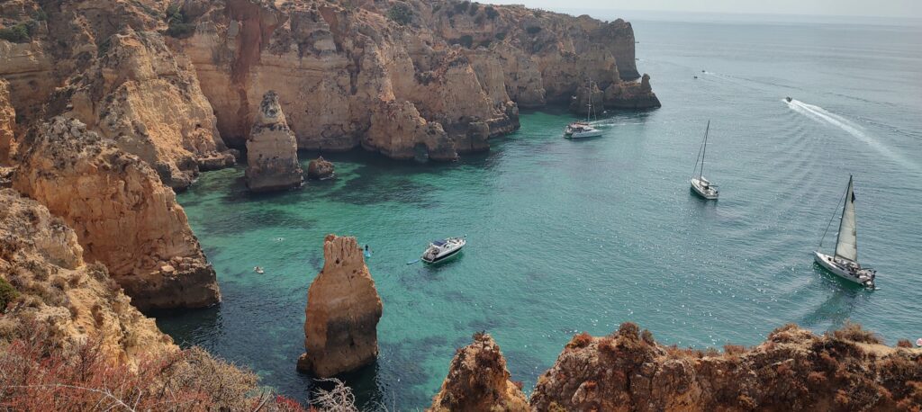 Cliff cove from above, turquoise water and boats, Portugal, 2024